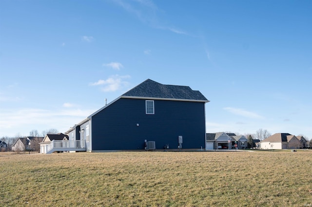 view of property exterior with a wooden deck, central AC, and a lawn