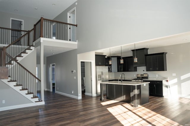 kitchen with sink, a breakfast bar, stainless steel appliances, dark hardwood / wood-style floors, and an island with sink