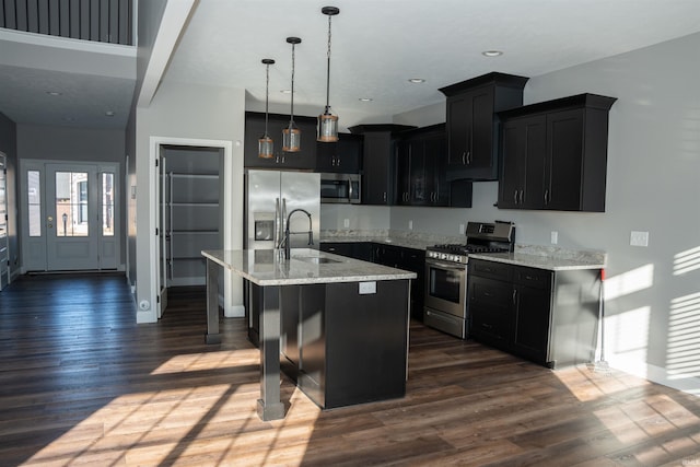 kitchen with a kitchen bar, sink, decorative light fixtures, a center island with sink, and appliances with stainless steel finishes