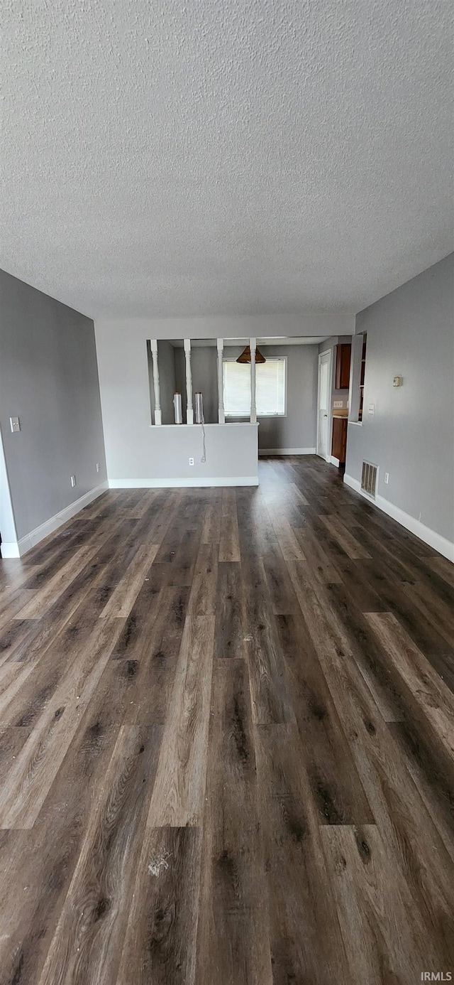 unfurnished living room with dark hardwood / wood-style flooring and a textured ceiling