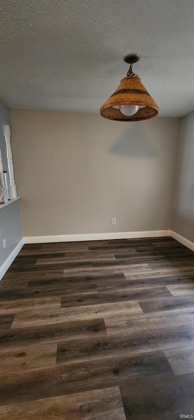 spare room featuring a textured ceiling and dark hardwood / wood-style flooring