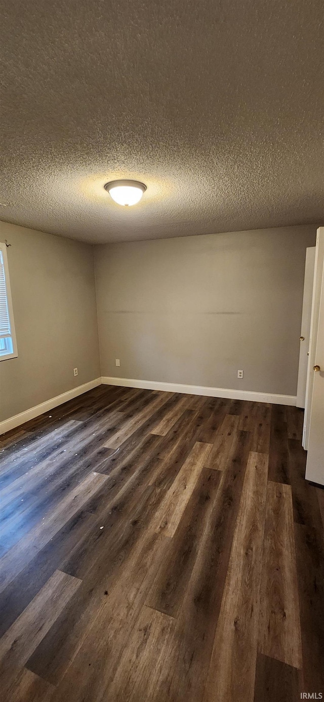 empty room featuring dark hardwood / wood-style floors and a textured ceiling