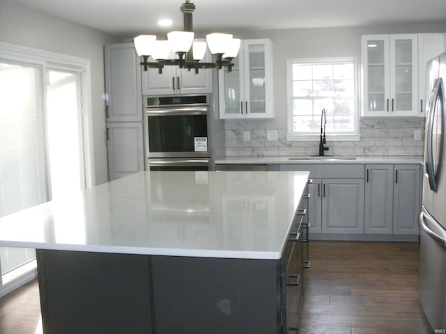 kitchen featuring sink, decorative light fixtures, dark hardwood / wood-style floors, a kitchen island, and stainless steel appliances