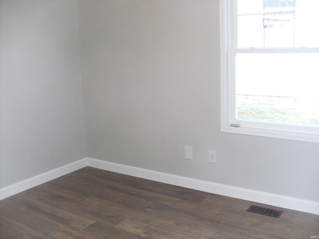 spare room with dark hardwood / wood-style flooring and a wealth of natural light