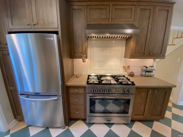 kitchen with appliances with stainless steel finishes, wall chimney exhaust hood, and backsplash