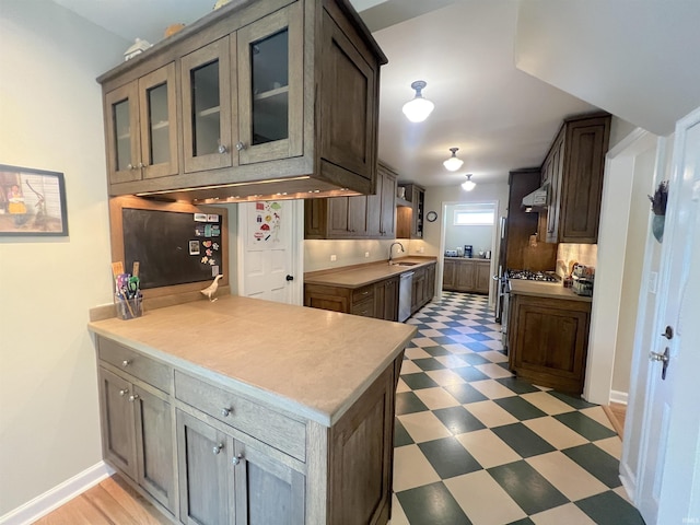 kitchen featuring dishwasher, dark brown cabinets, sink, and kitchen peninsula