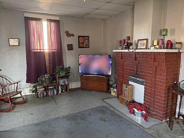 carpeted living room with a drop ceiling and a fireplace