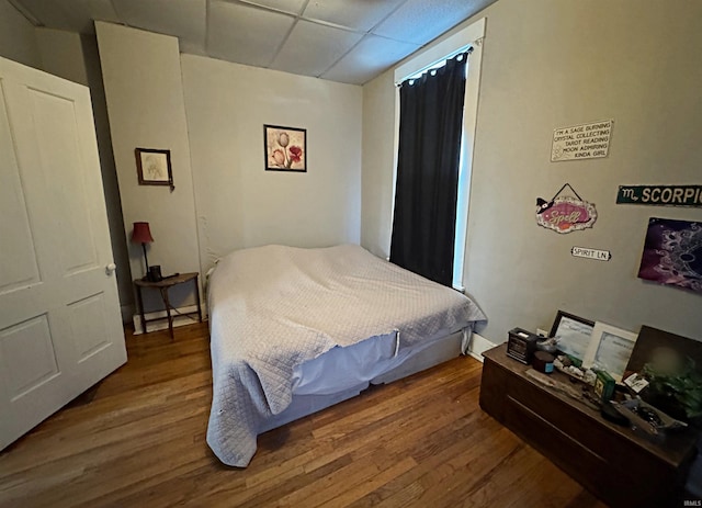 bedroom with wood-type flooring and a paneled ceiling