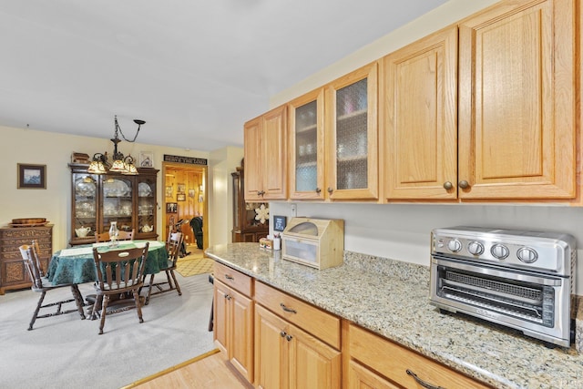 kitchen with light stone countertops, light wood-type flooring, and light brown cabinetry