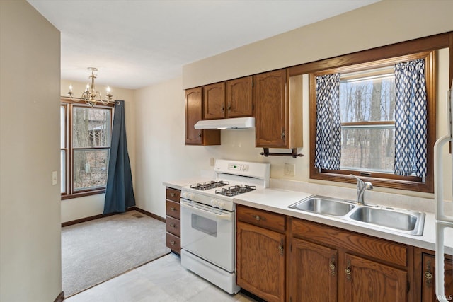 kitchen with sink, white gas range oven, hanging light fixtures, light colored carpet, and a chandelier