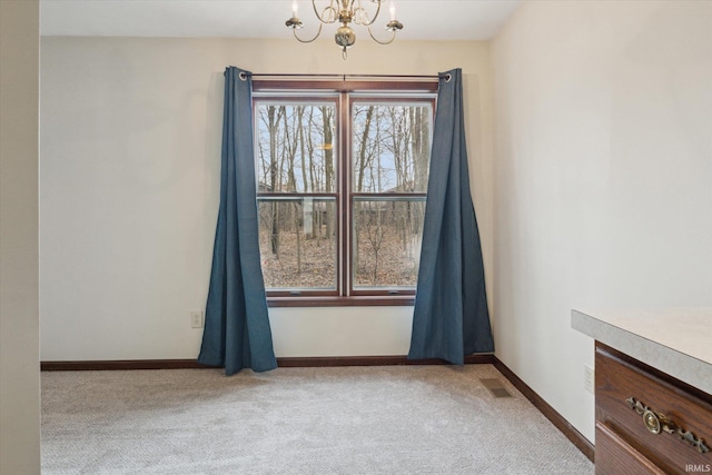 spare room with light carpet and a chandelier