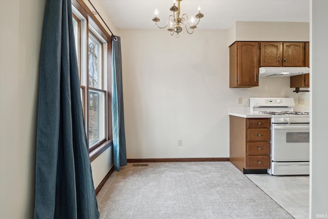 kitchen featuring light carpet, white gas range, hanging light fixtures, and a chandelier