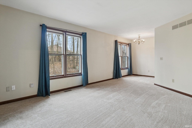 carpeted spare room featuring an inviting chandelier and plenty of natural light