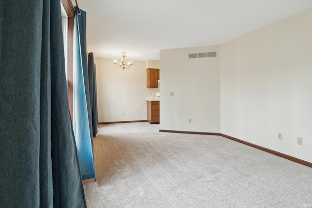 carpeted empty room with an inviting chandelier