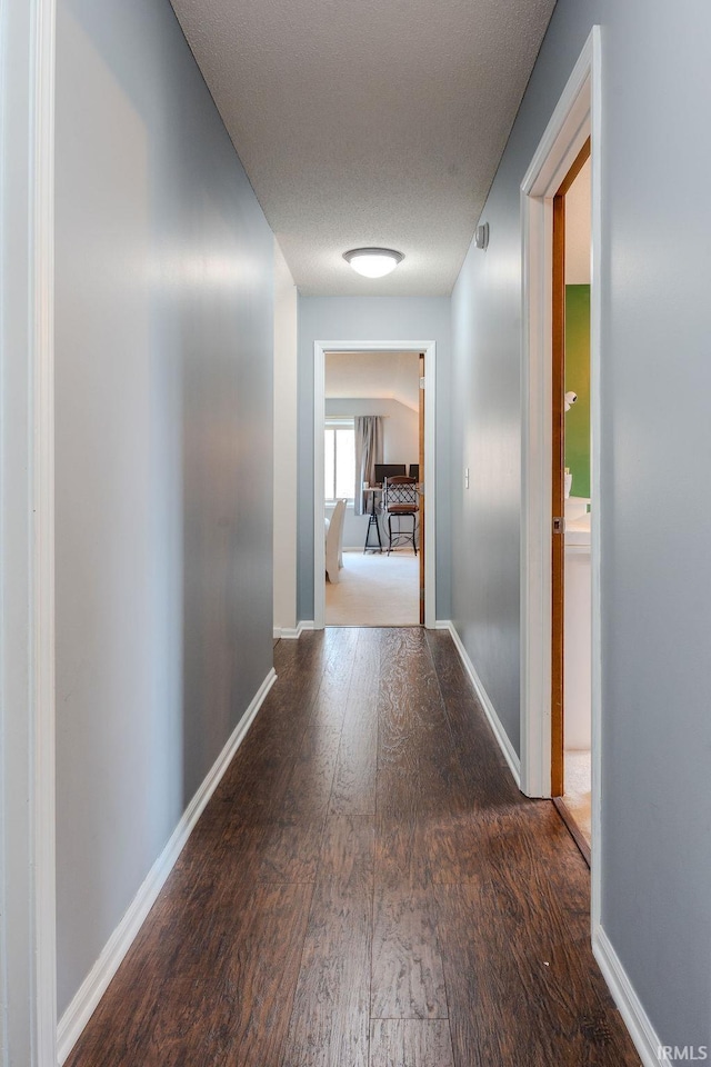 hall with dark hardwood / wood-style floors and a textured ceiling