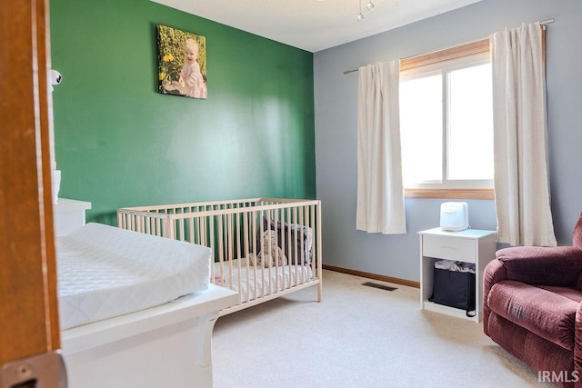 bedroom with light carpet and a nursery area