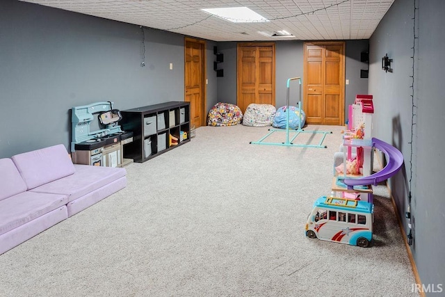 recreation room featuring carpet floors and a drop ceiling