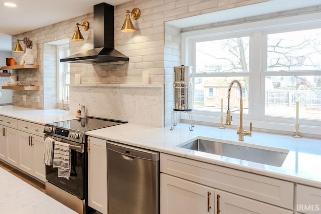 kitchen featuring wall chimney exhaust hood, sink, white cabinetry, stainless steel appliances, and light stone countertops