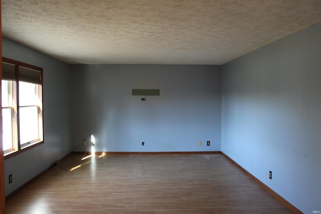 unfurnished room with hardwood / wood-style flooring and a textured ceiling