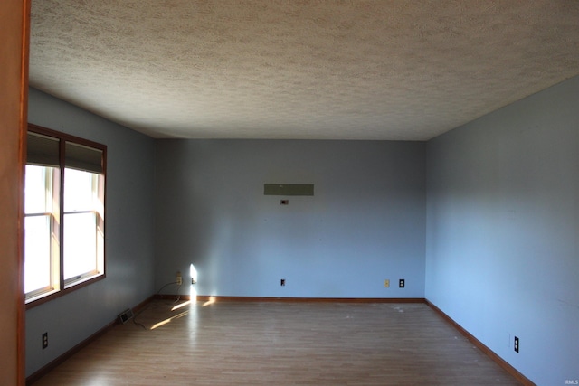 unfurnished room with hardwood / wood-style flooring and a textured ceiling