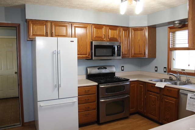 kitchen featuring stainless steel appliances, light hardwood / wood-style floors, sink, and a textured ceiling