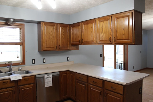 kitchen featuring sink, light hardwood / wood-style floors, a textured ceiling, stainless steel dishwasher, and kitchen peninsula