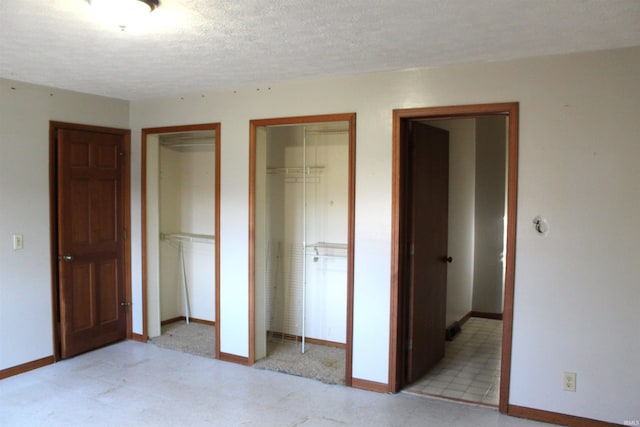 unfurnished bedroom featuring a textured ceiling and two closets