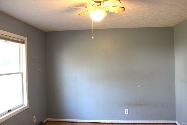 empty room with ceiling fan and a textured ceiling