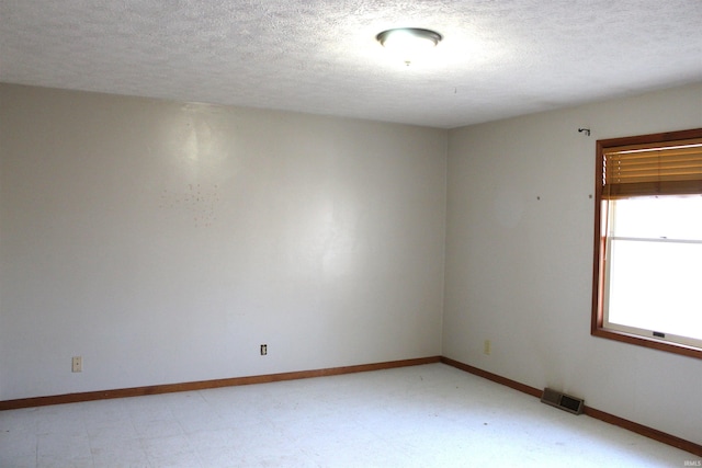 unfurnished room with a textured ceiling