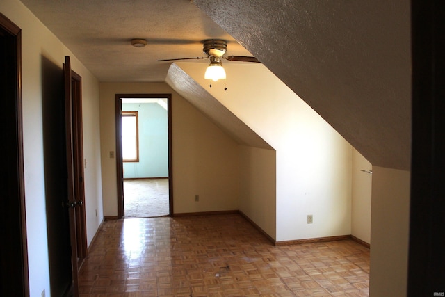 bonus room with light parquet flooring, vaulted ceiling, ceiling fan, and a textured ceiling