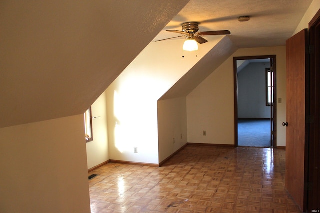 additional living space featuring light parquet flooring, lofted ceiling, ceiling fan, and a textured ceiling