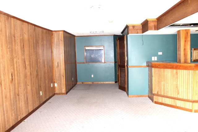 carpeted empty room featuring ornamental molding and wood walls