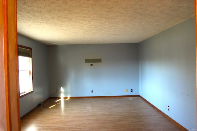 unfurnished room with hardwood / wood-style flooring and a textured ceiling