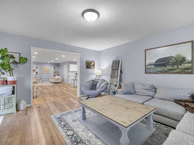 living room with a textured ceiling and light wood-type flooring