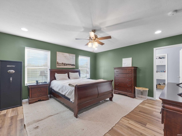 bedroom with ceiling fan, a textured ceiling, and light hardwood / wood-style floors