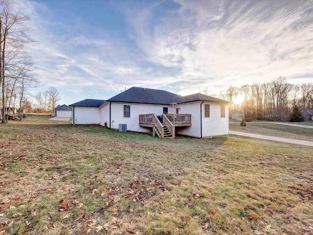 back house at dusk with a wooden deck, a garage, a lawn, and central air condition unit