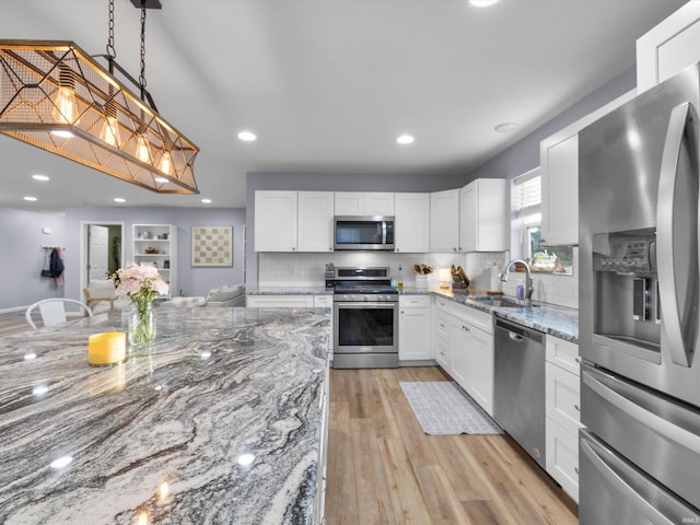 kitchen with white cabinetry, sink, light stone counters, and stainless steel appliances