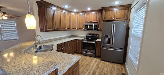 kitchen featuring light stone counters, hanging light fixtures, kitchen peninsula, and appliances with stainless steel finishes