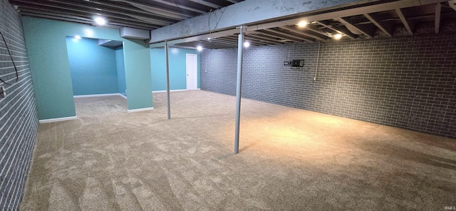 basement featuring brick wall and carpet floors