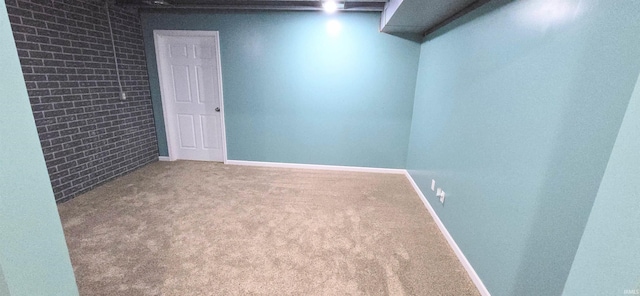 carpeted spare room with brick wall