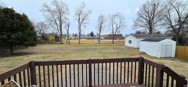 wooden terrace with a storage unit and a lawn