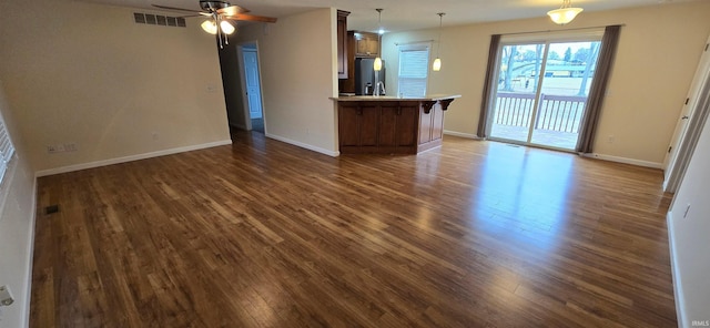 unfurnished living room featuring ceiling fan and dark hardwood / wood-style flooring