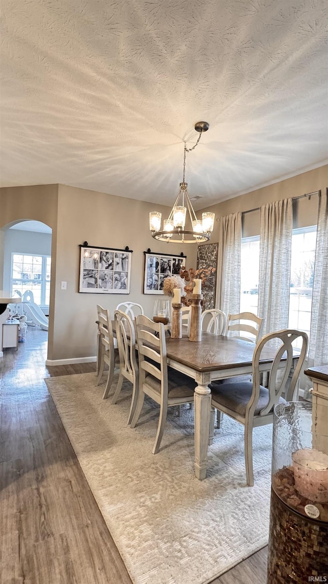 dining room featuring wood-type flooring, a textured ceiling, and a notable chandelier