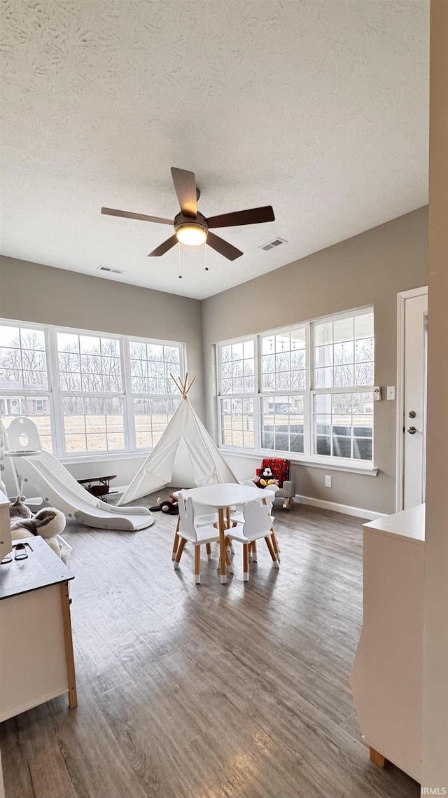 game room featuring hardwood / wood-style flooring, a textured ceiling, and ceiling fan