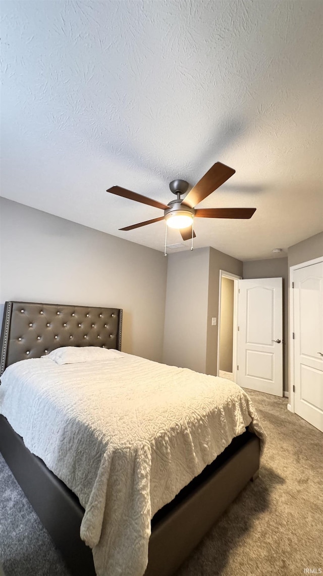 carpeted bedroom featuring a textured ceiling and ceiling fan