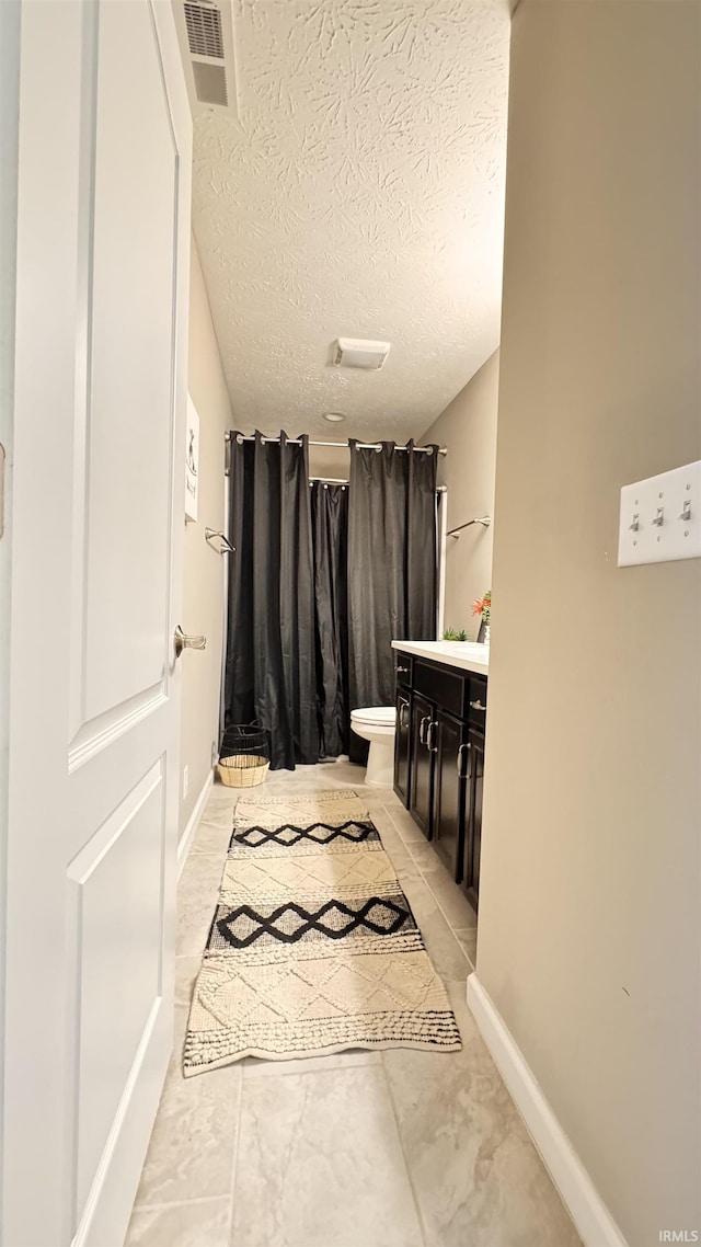 bathroom featuring walk in shower, vanity, toilet, and a textured ceiling