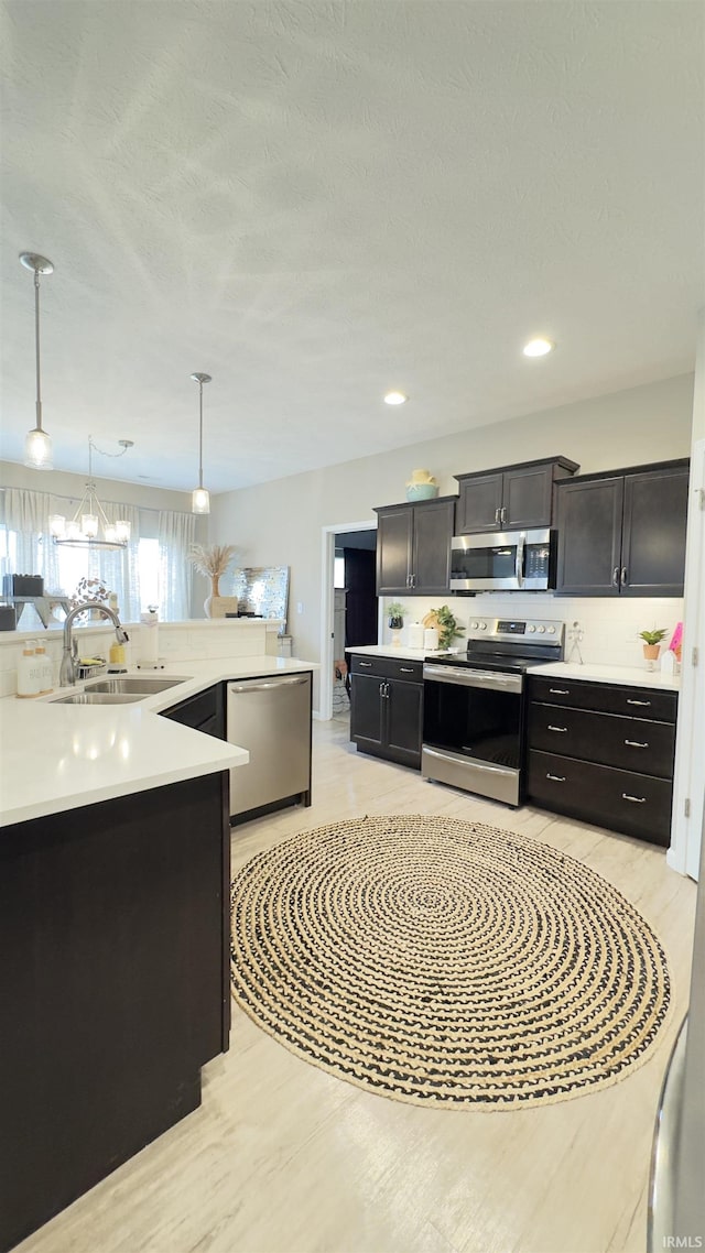 kitchen featuring stainless steel appliances, sink, and decorative light fixtures