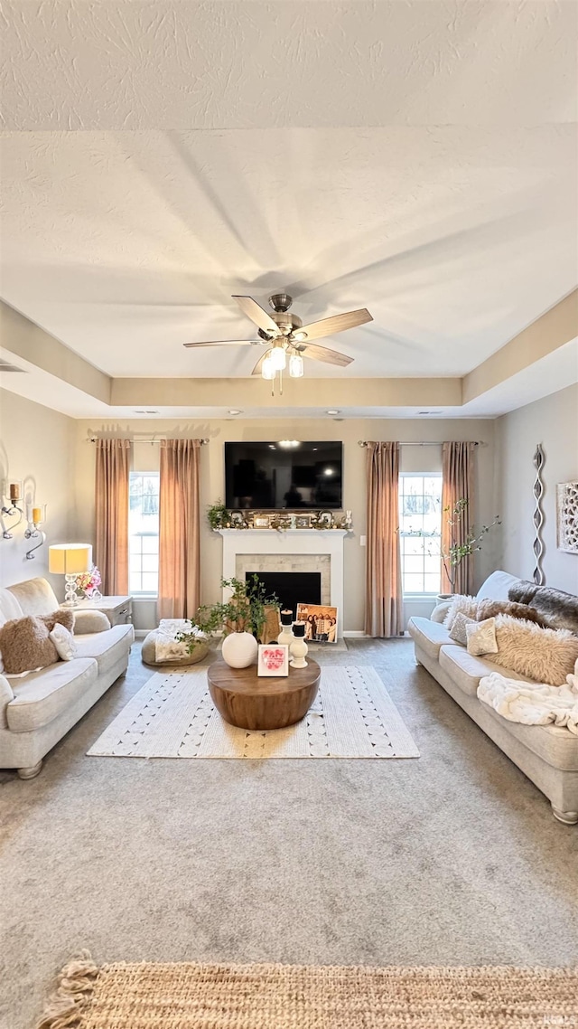 living room with a textured ceiling, a wealth of natural light, ceiling fan, and carpet flooring