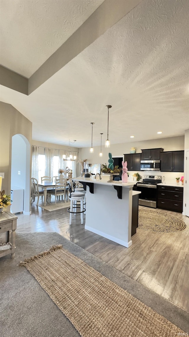 kitchen with a kitchen island, decorative light fixtures, a kitchen breakfast bar, stainless steel appliances, and a textured ceiling