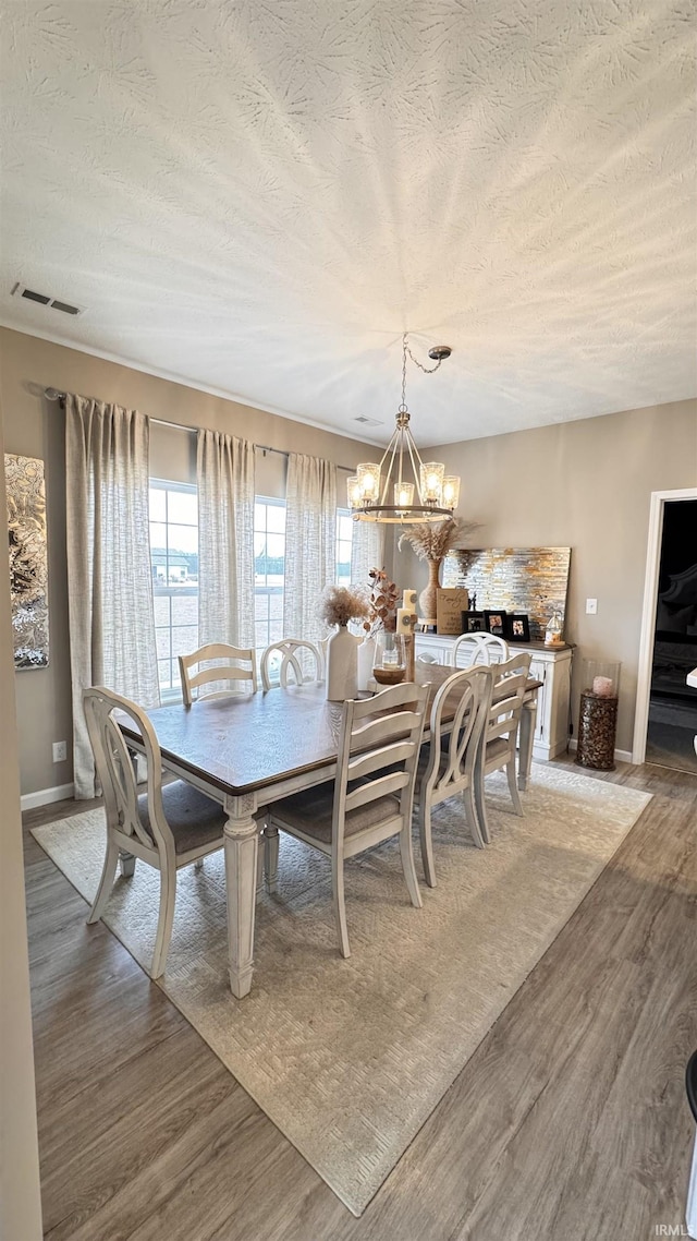 dining area featuring hardwood / wood-style floors, a textured ceiling, and a chandelier